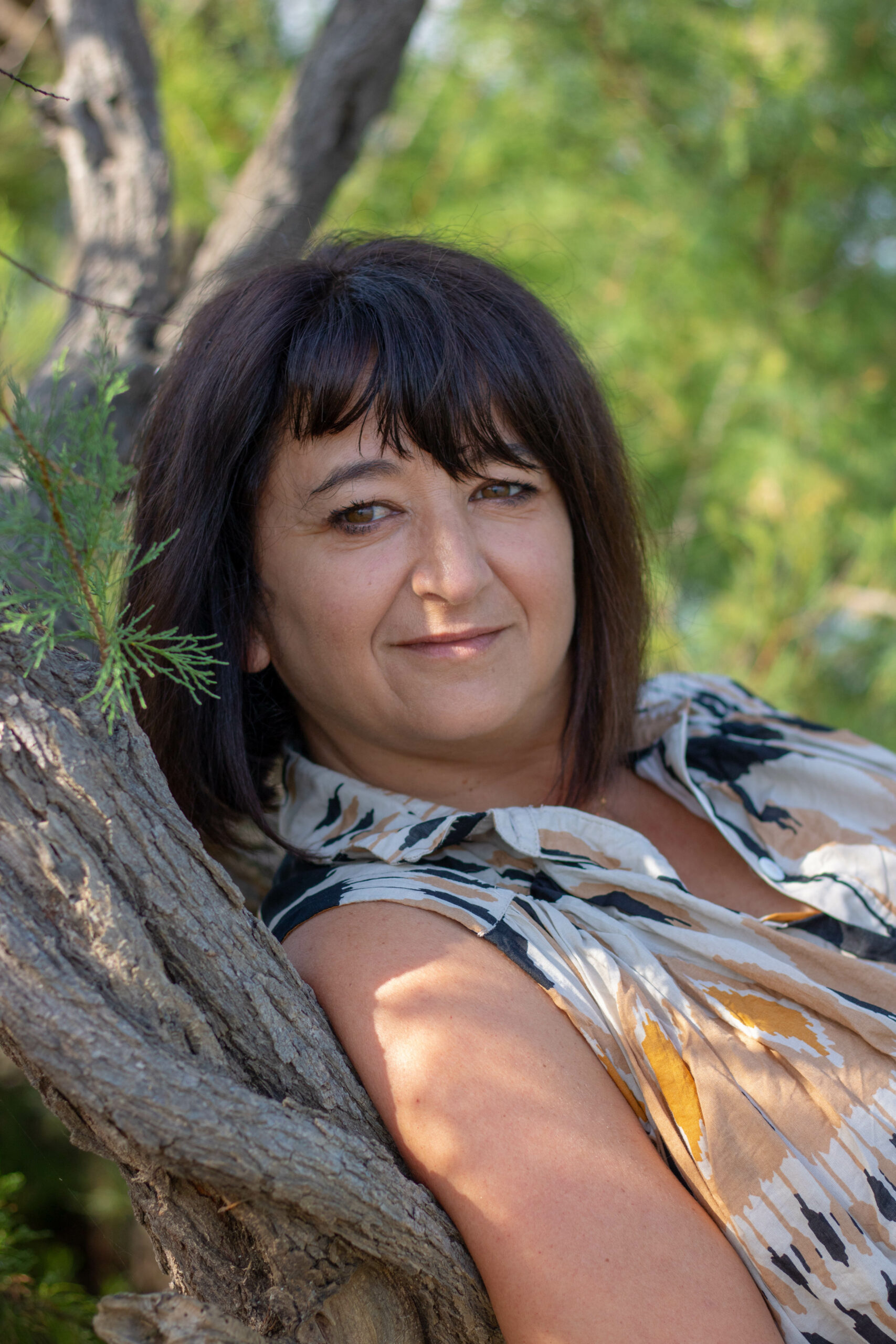 Portrait d'Isabelle Mayoral, sophrologue, souriante, adossée à un arbre